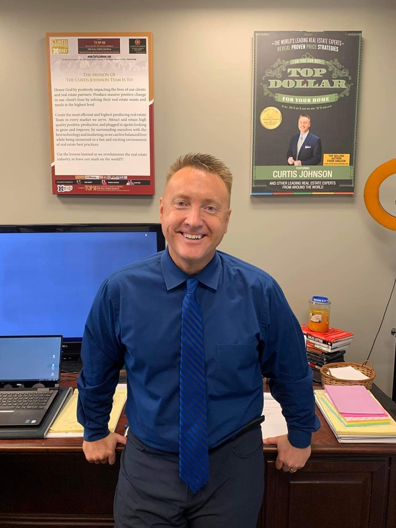 Curtis Johnson in his office beneath his WSJ Top 50 award and Top Dollar book poster